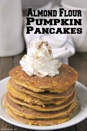 easy gluten free pumpkin pancakes stacked on plate with whipped cream and pumpkin spice