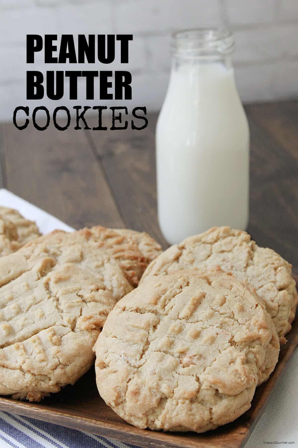 wood tray of large peanut butter cookies and glass of milk