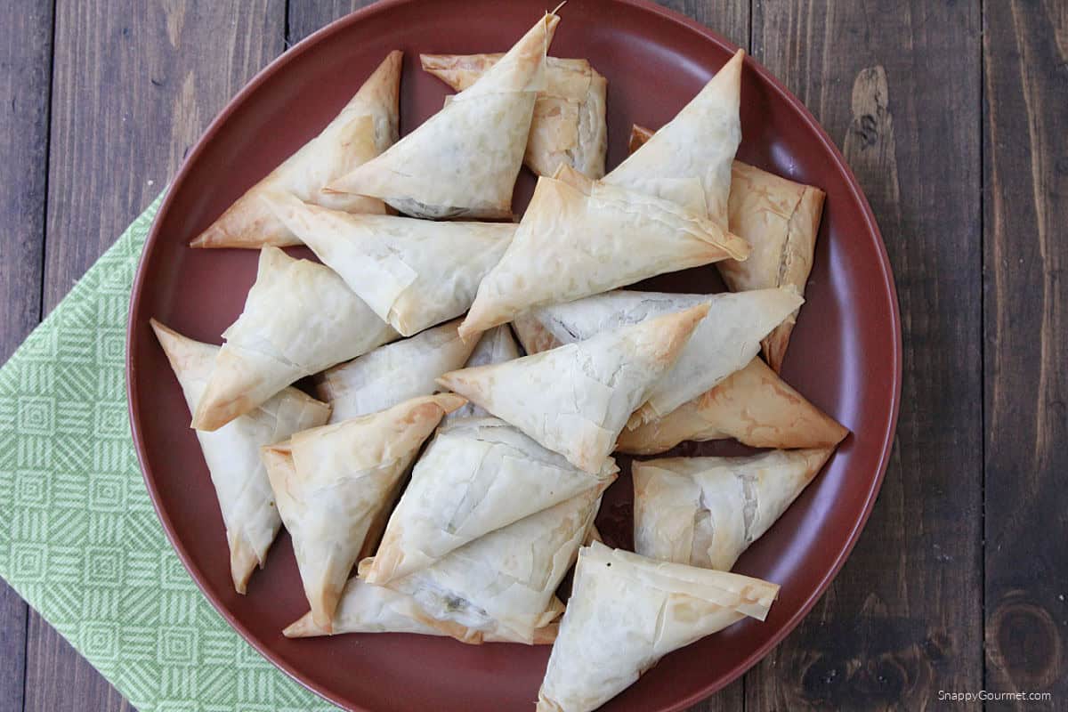 Spinach & Feta Phyllo Turnovers stacked on plate with napkin on side