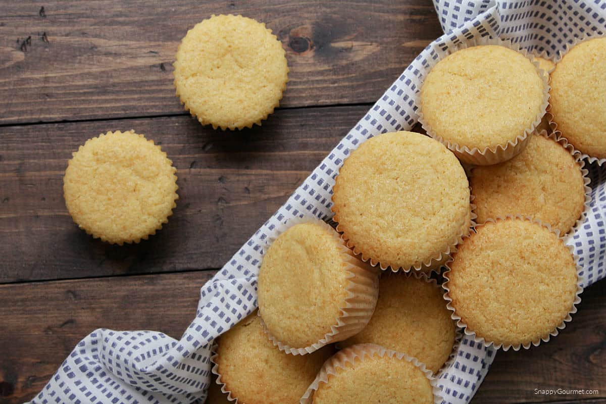 kitchen towel topped with cornbread muffins in paper liners