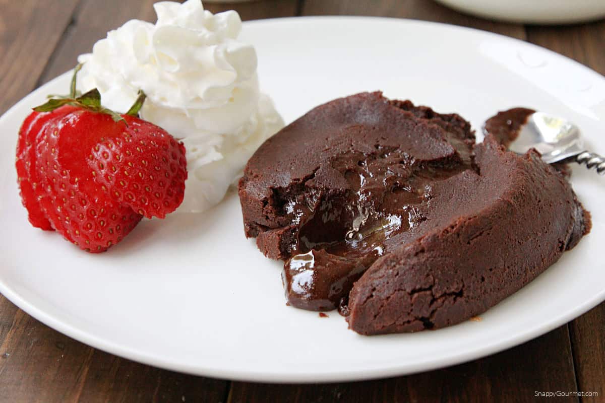 Chocolate Molten Lava Cake with spoon, strawberry, and whipped cream on plate