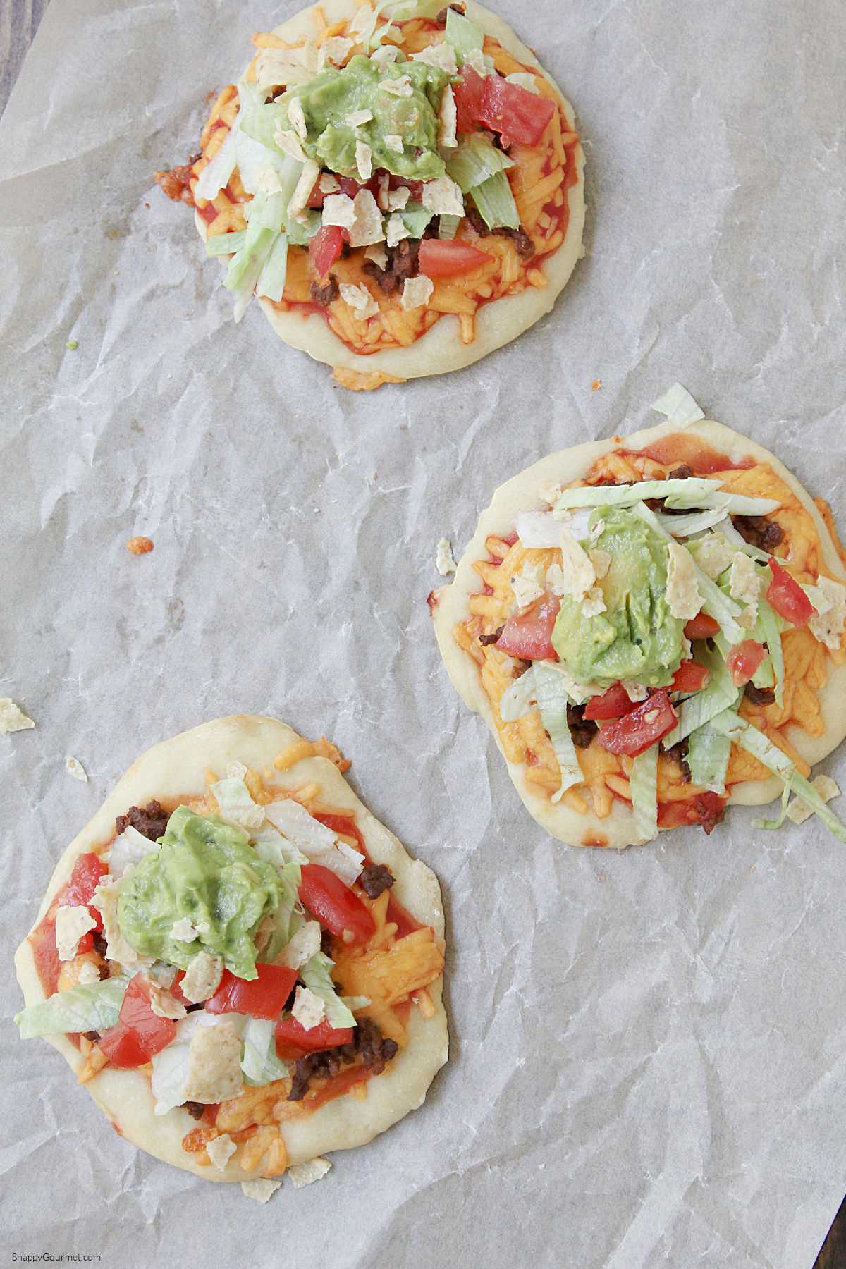 Taco Pizzas three small Taco Pizzas on parchment paper